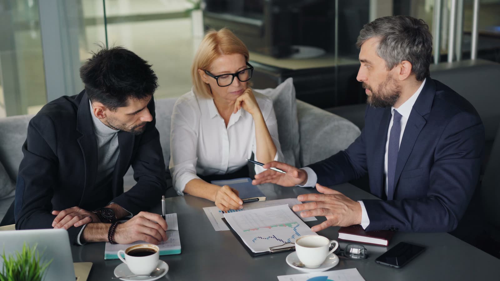 Tres profesionales analizando gráficos en una reunión